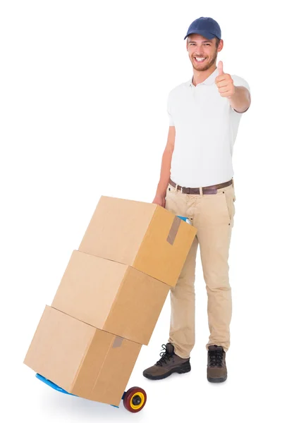 Happy delivery man pushing trolley of boxes — Stock Photo, Image