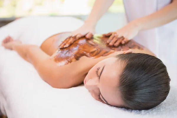 Attractive woman receiving chocolate back mask at spa center — Stock Photo, Image