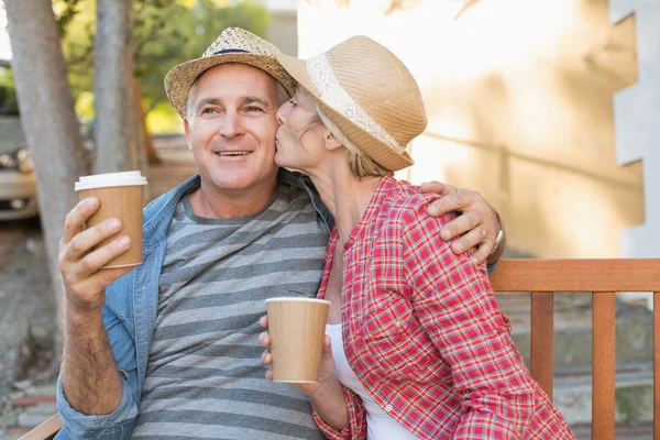 Glückliches älteres Paar trinkt Kaffee auf einer Bank in der Stadt — Stockfoto