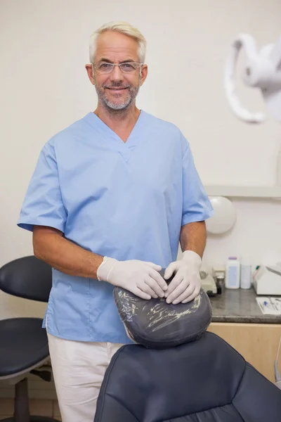Стоматолог улыбается в камеру рядом со стулом — стоковое фото