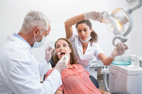 Dentista examinando los dientes de un paciente — Foto de Stock