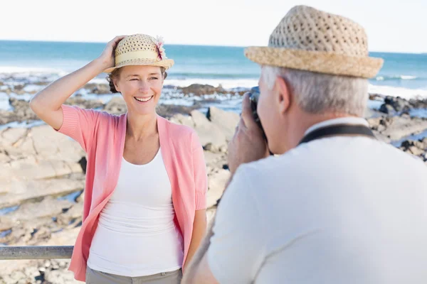 Feliz hombre casual tomando una foto de su pareja junto al mar — Foto de Stock