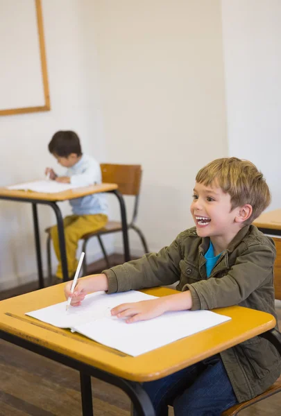 Uczeń pisze w notatniku na jego biurko — Zdjęcie stockowe