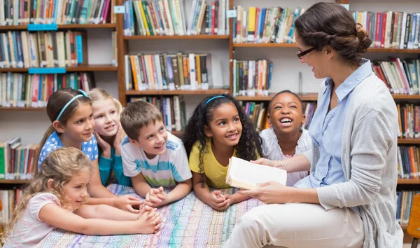 Pupils and teacher reading in library — Stock Photo, Image