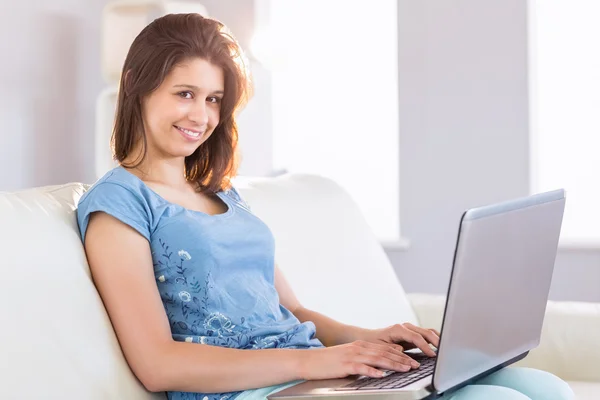 Mooie brunette ontspannen op de Bank met behulp van laptop — Stockfoto