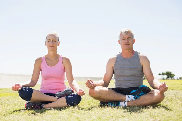 Ouder paar in lotus pose op het gras zitten passen — Stockfoto