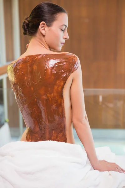 Aantrekkelijke vrouw met chocolade terug masker op spa center — Stockfoto