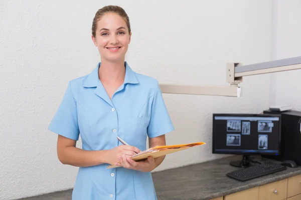 Dental assistant writing in folder — Stock Photo, Image
