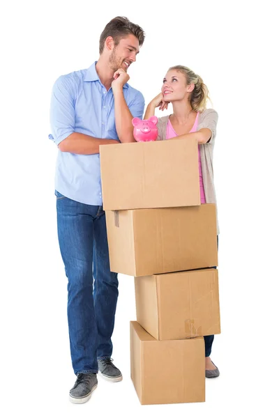Atractiva pareja joven apoyada en cajas con alcancía — Foto de Stock