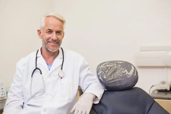 Dentista sonriendo a la cámara junto a la silla —  Fotos de Stock