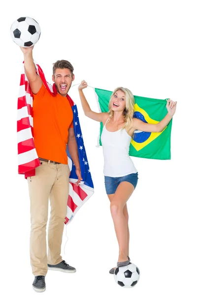 Emocionada pareja de aficionados de fútbol sosteniendo EE.UU. y la bandera de Brasil — Foto de Stock