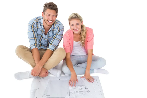 Attractive young couple sitting looking at blueprint — Stock Photo, Image