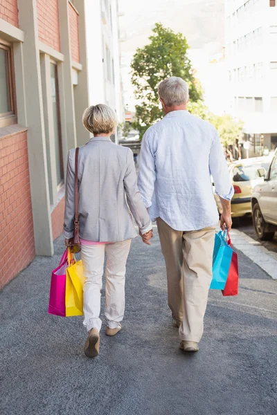 Happy mature couple walking with their shopping purchases — Stock Photo, Image