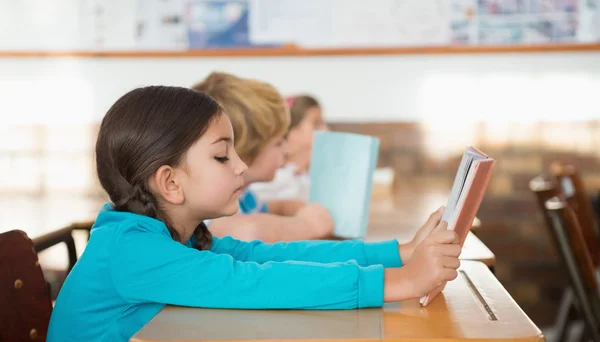 Pupils sitting in classroom reading books — Stock Photo, Image