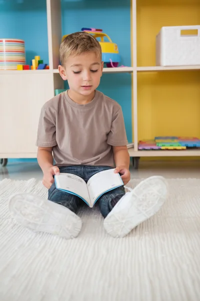 Menino no chão lendo em sala de aula — Fotografia de Stock