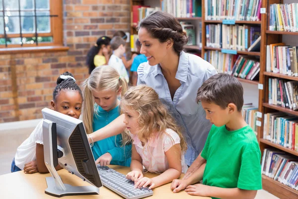 Elever och lärare tittar på en dator i biblioteket — Stockfoto