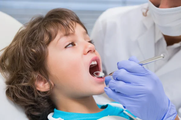 Odontólogo pediátrico examinando los dientes de un niño pequeño en los dentistas — Foto de Stock