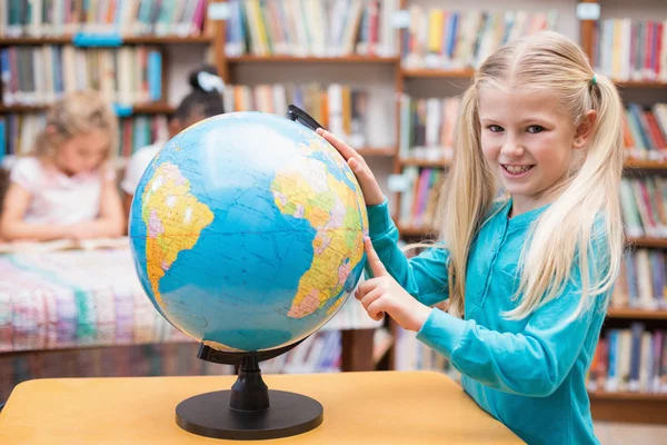 Schattig leerling kijken naar globe in bibliotheek — Stockfoto