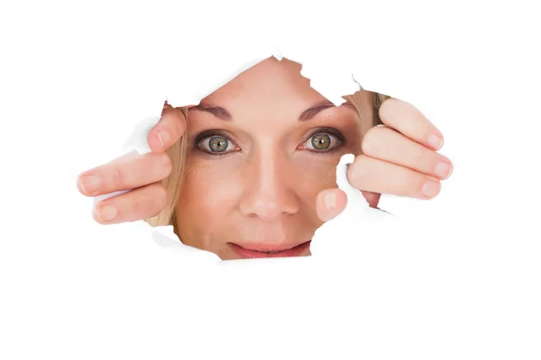 Woman looking through torn paper — Stock Photo, Image