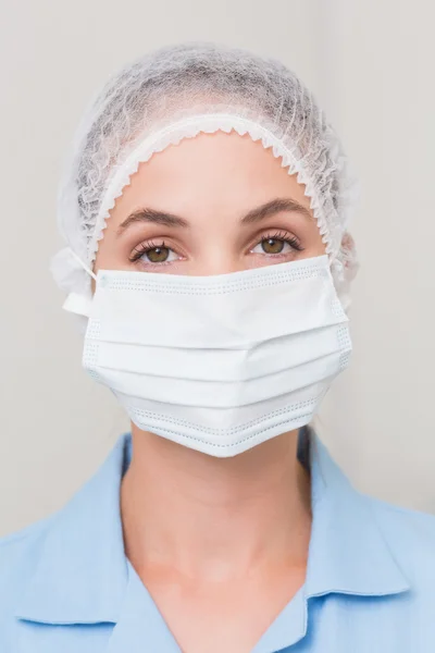 Стоматолог в хирургической маске и кепке смотрит в камеру — стоковое фото
