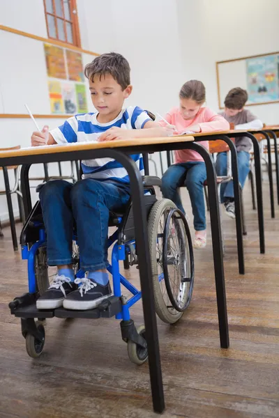 Handikappade eleven skriver i klassrummet — Stockfoto