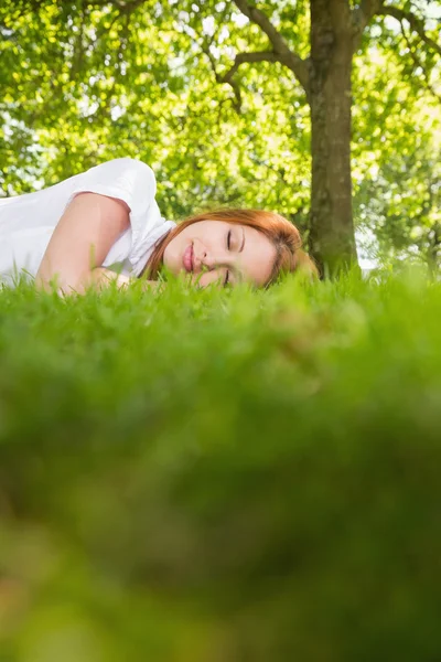 Mooie roodharige liggen op het gras — Stockfoto