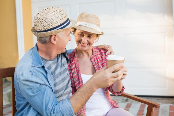 Happy mature couple drinking coffee on a bench in the city — Stock Photo, Image