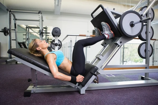 Vista lateral de la mujer en forma haciendo prensas de pierna en el gimnasio —  Fotos de Stock