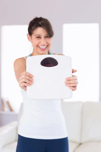 Ajuste morena sonriendo a la cámara sosteniendo escalas —  Fotos de Stock