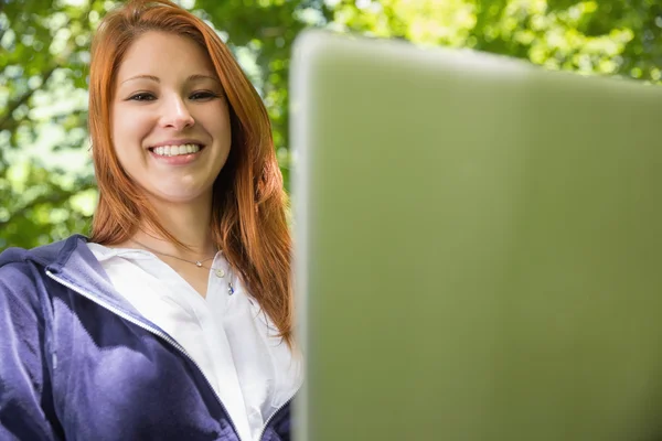 Redhead relaxing in the park using laptop — Stock Photo, Image