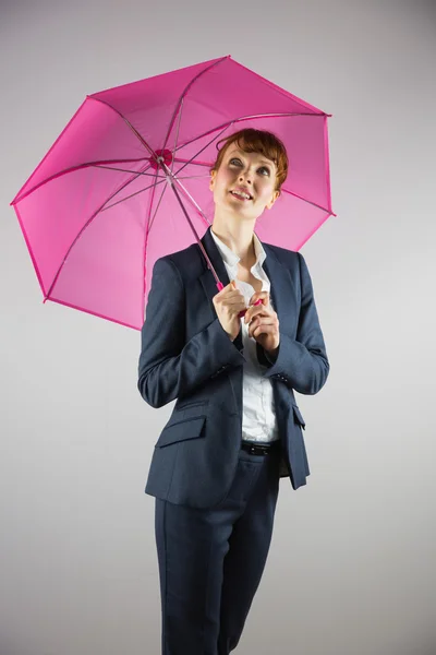 Mujer de negocios sonriente sosteniendo paraguas rosa — Foto de Stock