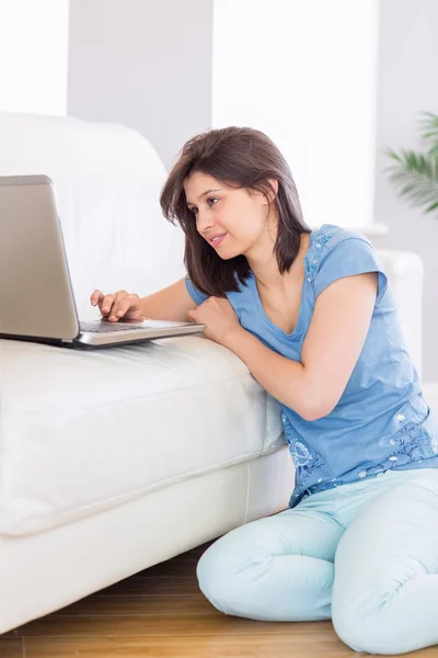 Pretty brunette using laptop on the couch — Stock Photo, Image