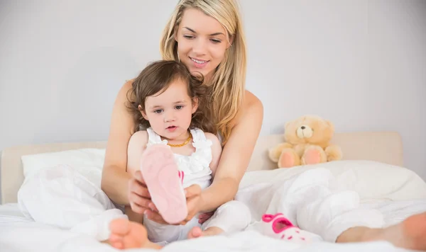 Madre ayudando a su hija a llevar su zapato en la cama — Foto de Stock