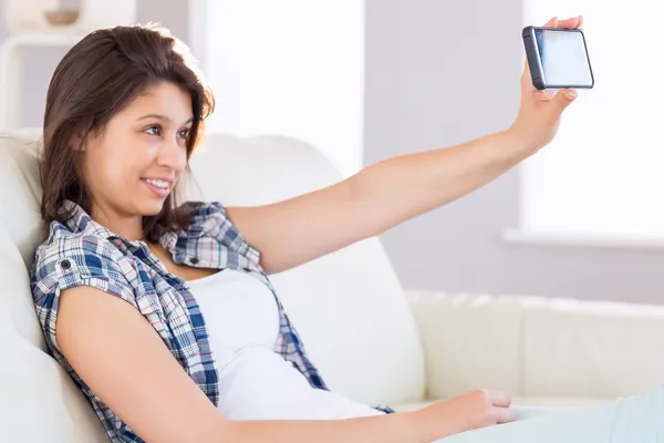 Bonita morena tomando una selfie en el sofá — Foto de Stock