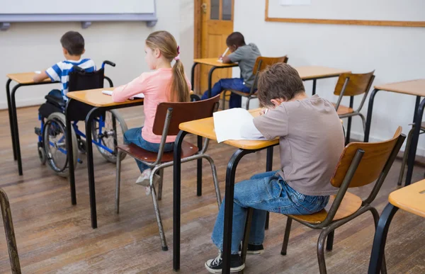 Disabled pupil writing in classroom — Stock Photo, Image