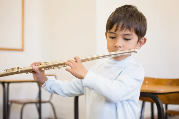 Pupil playing flute in classroom — Stock Photo, Image