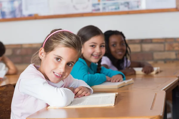 Alumnos leyendo libros en sus escritorios — Foto de Stock