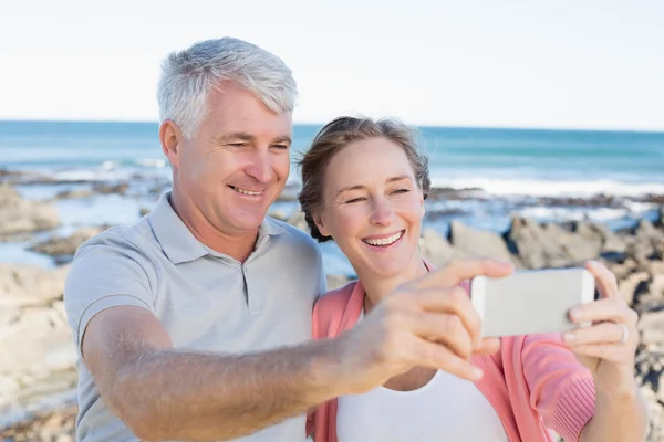 Feliz pareja casual tomando una selfie por la costa — Foto de Stock
