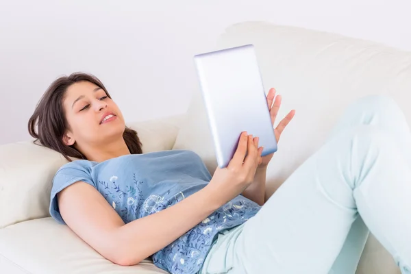 Hübsche Brünette mit ihrem Tablet-PC auf der Couch — Stockfoto