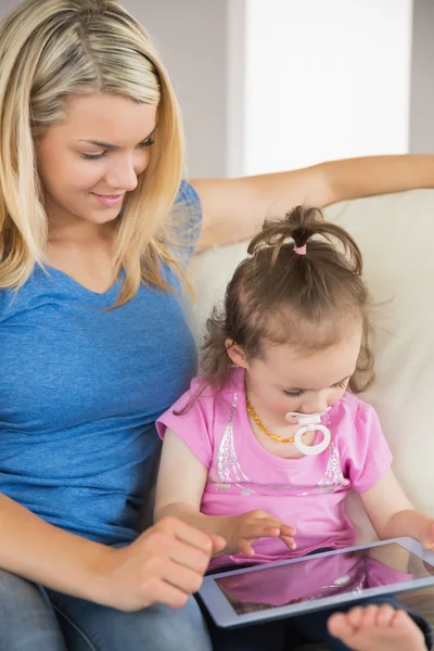 Mother and daughter using digital tablet on couch — Stock Photo, Image