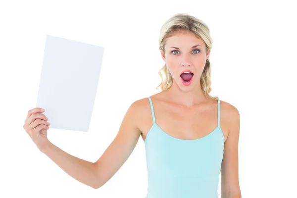 Schockierte Blondine hält ein Blatt Papier in der Hand — Stockfoto