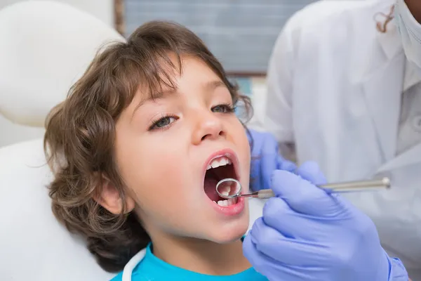 Odontólogo pediátrico examinando los dientes de un niño pequeño en los dentistas — Foto de Stock