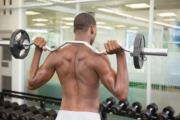 Homem sem camisa levantando barbell no ginásio — Fotografia de Stock