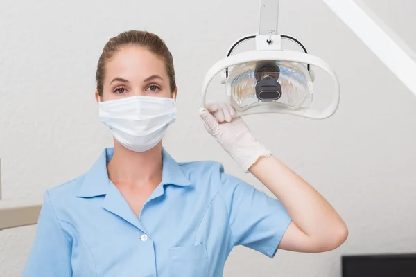 Dental assistant in mask holding light — Stock Photo, Image