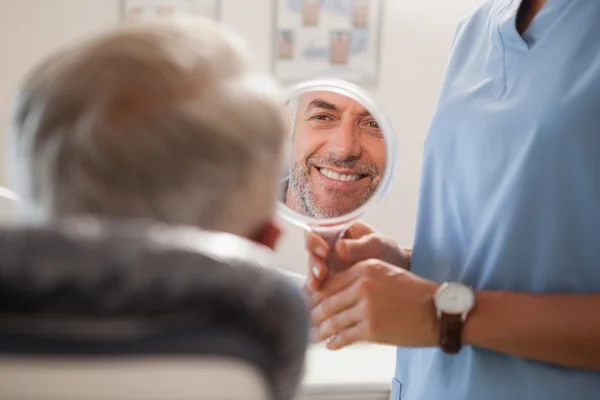 Dentista mostrando paciente seu novo sorriso — Fotografia de Stock