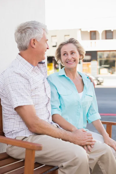 Glad äldre par som sitter på bänken i staden — Stockfoto