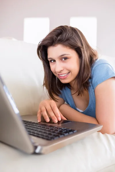 Mooie brunette met behulp van laptop op de Bank — Stockfoto
