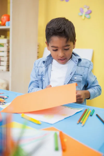 Niño pequeño cortando formas de papel — Foto de Stock