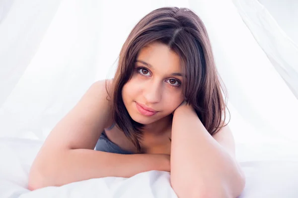 Piękna brunetka uśmiecha się do kamery na łóżku — Zdjęcie stockowe
