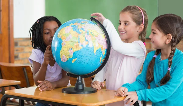 Pupils sitting in classroom with globe — Stock Photo, Image